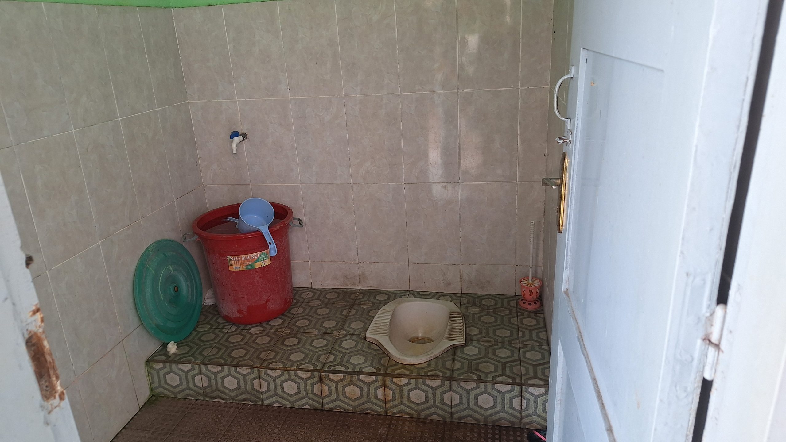 Gambar menunjukkan situasi kamar mandi. Ada WC, bak yang terisi dengan air dan gayung, serta peralatan kamar mandi lainnyaa