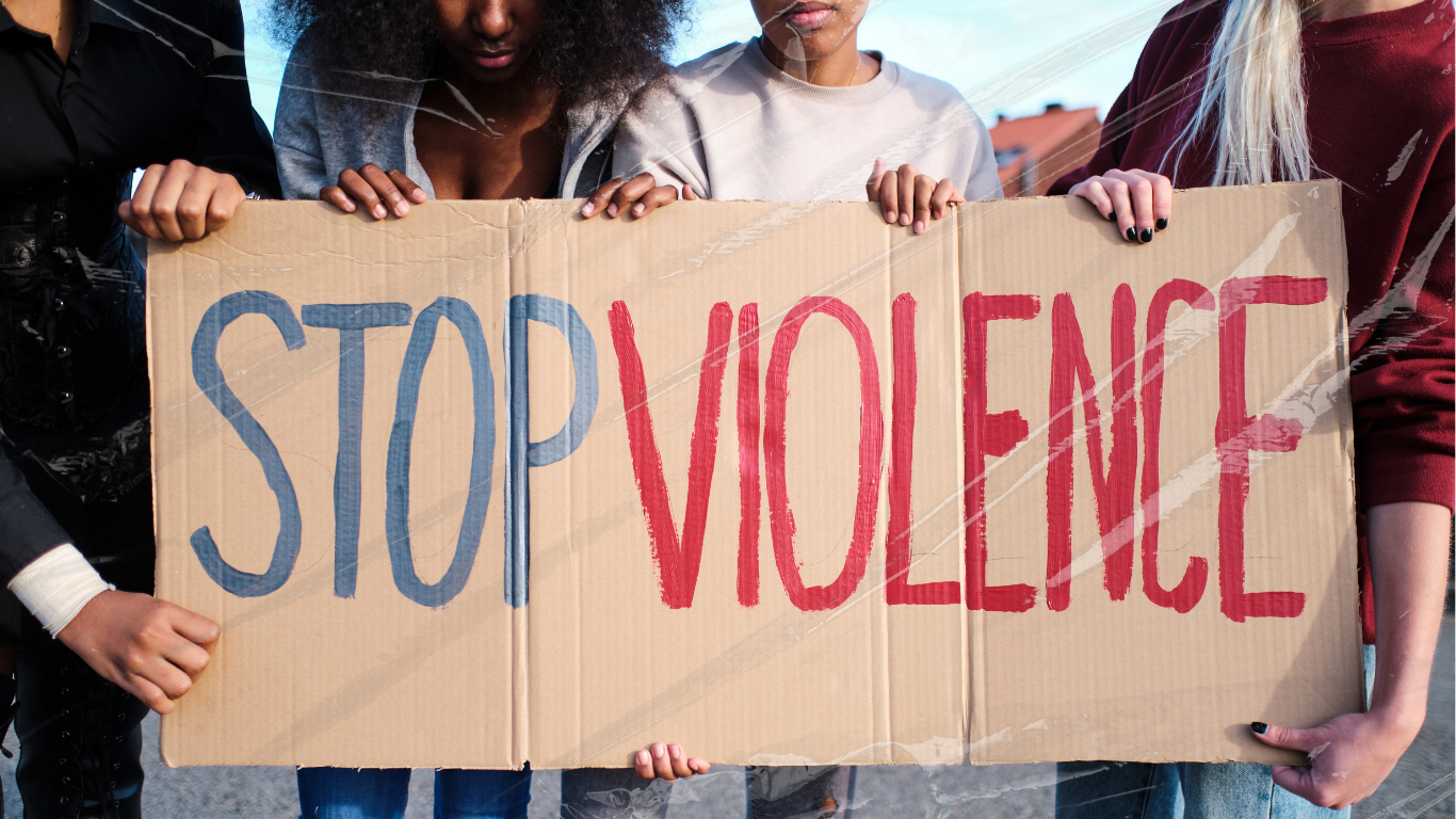 foto menunjukkan beberapa orang laki laki dan perempuan sedang memegang kertas yang bertuliskan stop violence atau hentikan kekerasan